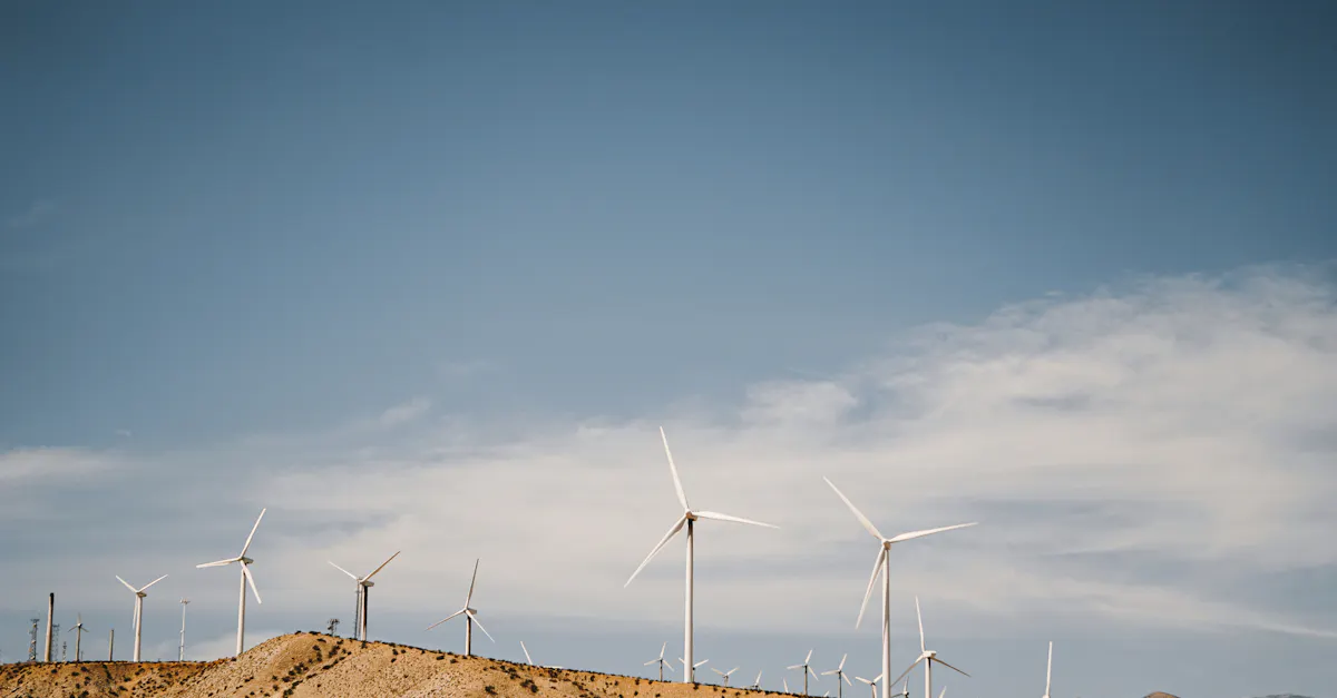 Stunning view of wind turbines on a desert hill under a clear blue sky, showcasing renewable energy.